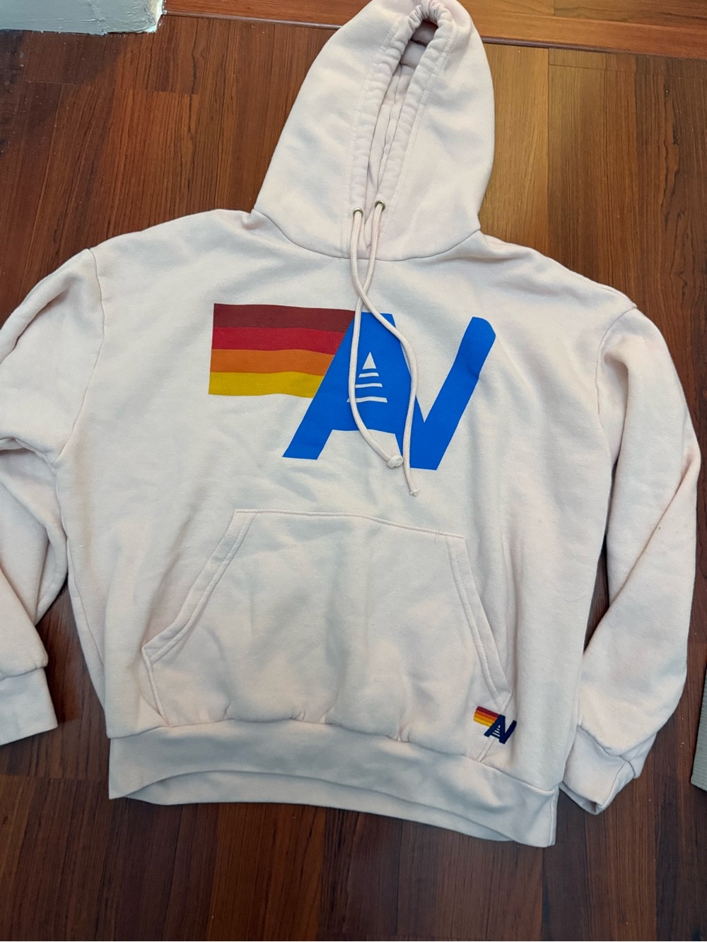 Aviator Nation Cream Hoodie with Blue Logo and Red-Orange-Yellow Stripe